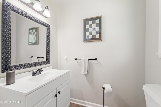 half bathroom with toilet, vanity, and baseboards