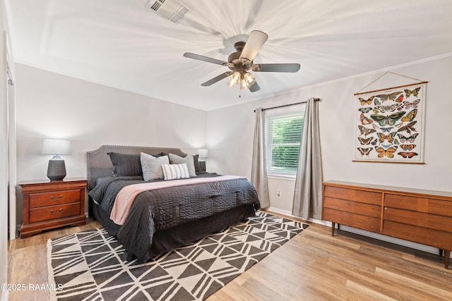 bedroom with wood finished floors, visible vents, ceiling fan, and ornamental molding