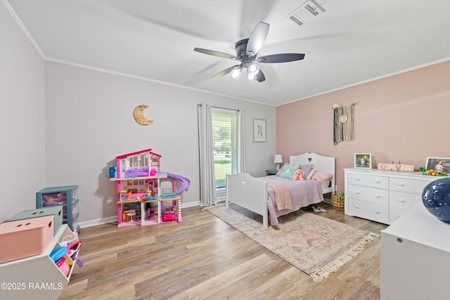bedroom featuring light wood-style floors, crown molding, visible vents, and baseboards