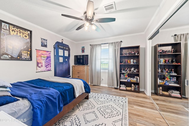 bedroom with crown molding, visible vents, wood finished floors, and baseboards