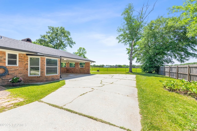 view of yard featuring a patio, driveway, and fence
