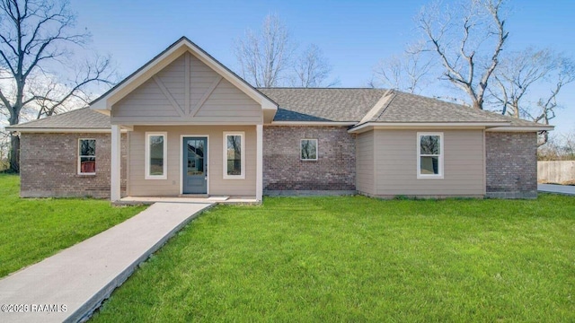 back of property with a lawn, roof with shingles, and brick siding