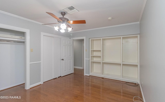 110 Karen Dr, Lafayette, LA 70503 - unfurnished bedroom featuring two closets, crown molding, visible vents, baseboards, and wood finished floors