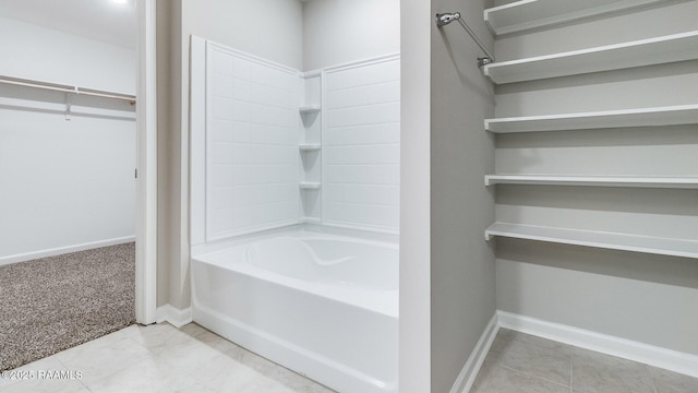 full bathroom featuring tile patterned floors, a walk in closet, tub / shower combination, and baseboards