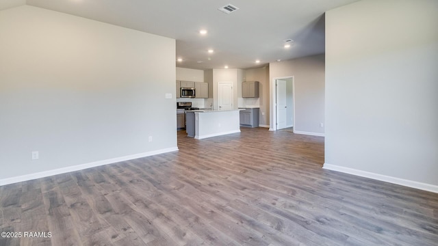 unfurnished living room with recessed lighting, visible vents, wood finished floors, and baseboards