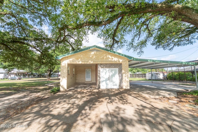 exterior space featuring a storage shed, an attached carport, and concrete driveway