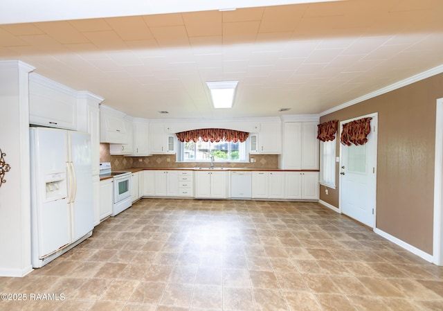 kitchen with white appliances, baseboards, white cabinetry, tasteful backsplash, and a sink