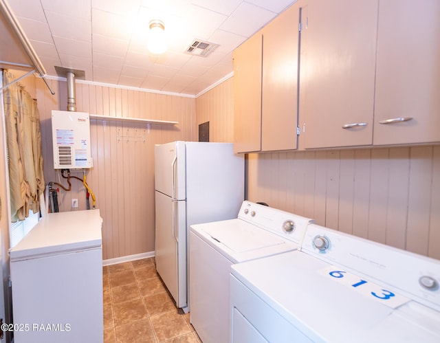 washroom featuring visible vents, washing machine and dryer, wooden walls, cabinet space, and water heater