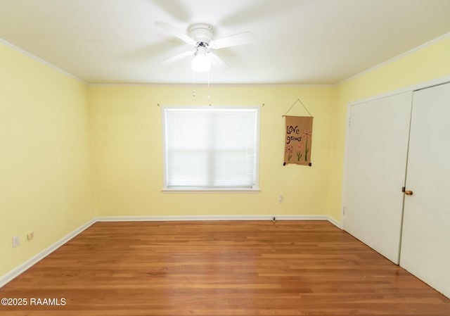 unfurnished bedroom featuring baseboards, a ceiling fan, a closet, and wood finished floors