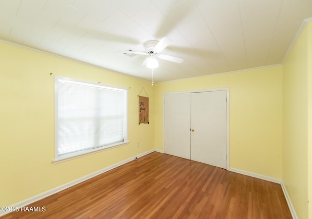 unfurnished bedroom with crown molding, a ceiling fan, wood finished floors, and a closet