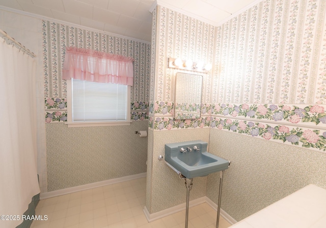 bathroom with a sink, baseboards, and ornamental molding