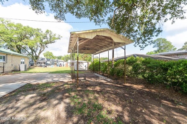 view of yard featuring a detached carport, central AC, and driveway