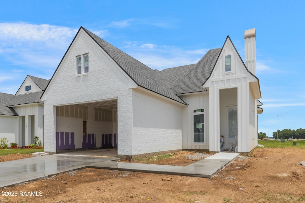 100 Alexander Palm Ave, Youngsville, LA 70592 - modern farmhouse style home with driveway, roof with shingles, board and batten siding, a garage, and a chimney