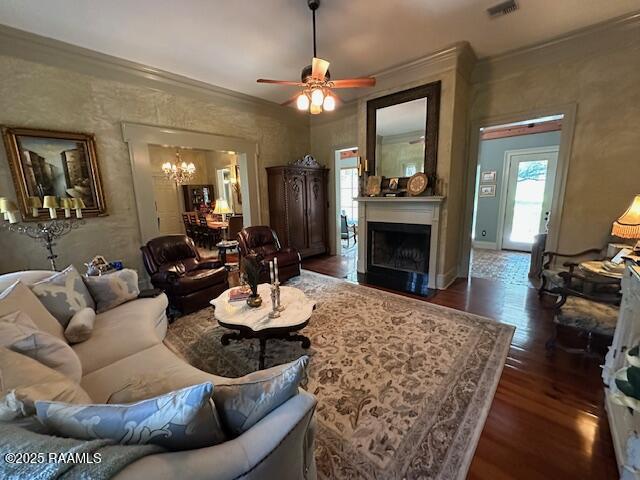 10427 U S Highway 167, Abbeville, LA 70510 - living room featuring crown molding, ceiling fan with notable chandelier, a fireplace with flush hearth, visible vents, and dark wood-style floors