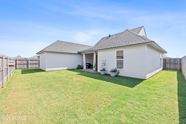 rear view of house featuring a fenced backyard, roof with shingles, and a yard