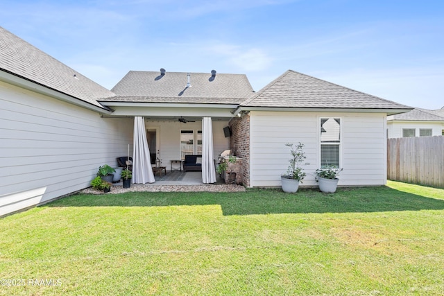 rear view of house with ceiling fan, roof with shingles, a lawn, a patio area, and fence