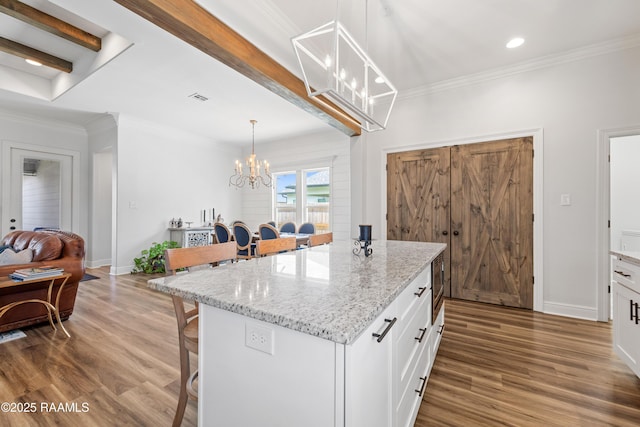 kitchen with white cabinets, a kitchen breakfast bar, wood finished floors, and a notable chandelier