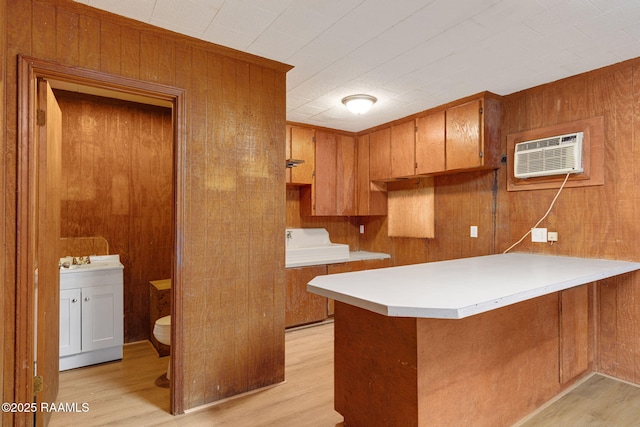 204 Tillou Andrus Dr, Opelousas, LA 70570 - kitchen featuring light wood-type flooring, wood walls, a peninsula, and brown cabinets