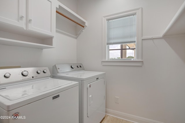 laundry room with baseboards, light tile patterned flooring, cabinet space, and washer and clothes dryer