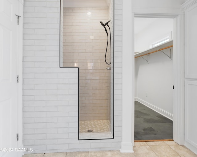 bathroom with baseboards, a tile shower, and tile patterned flooring