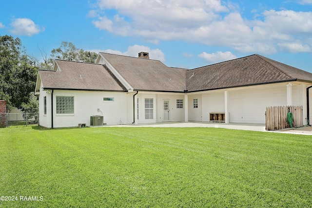 back of property featuring a lawn, roof with shingles, central AC unit, and fence