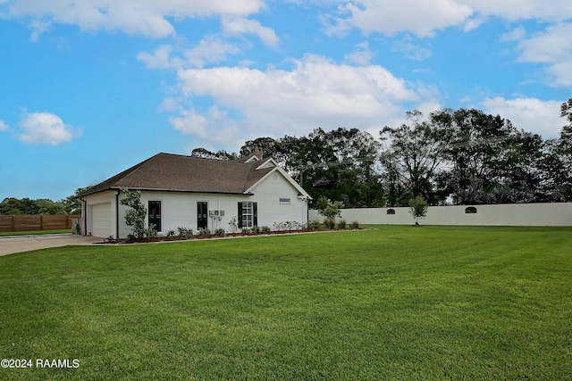 view of front facade with a front lawn, driveway, a garage, and fence