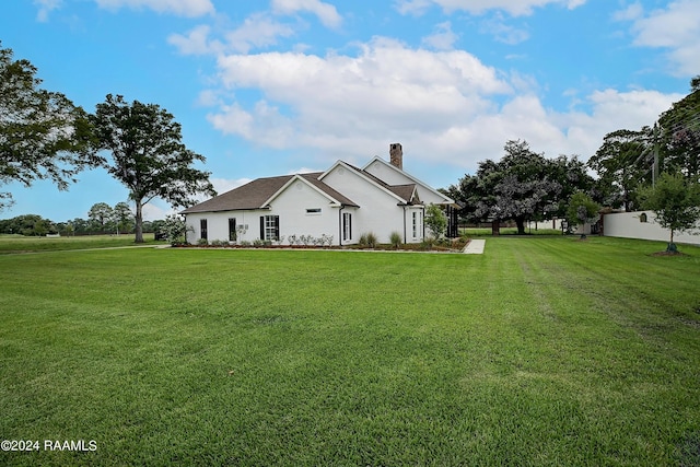 exterior space with a chimney, fence, and a lawn