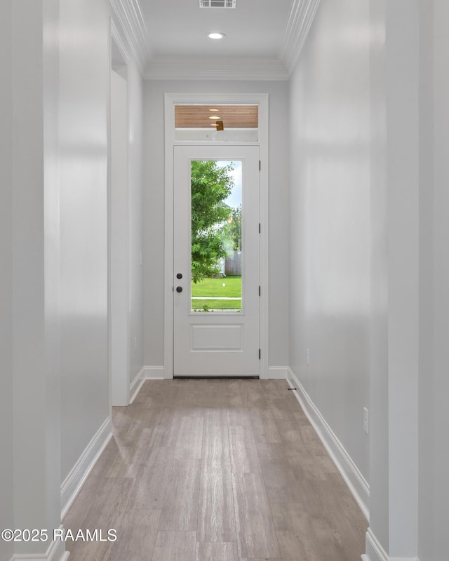 doorway to outside with ornamental molding, visible vents, wood finished floors, and baseboards