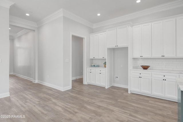 kitchen with light countertops, light wood-type flooring, tasteful backsplash, white cabinetry, and baseboards