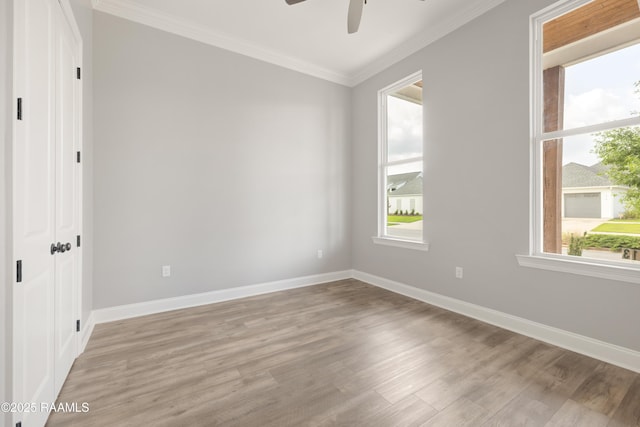 empty room with ceiling fan, light wood-type flooring, ornamental molding, and baseboards