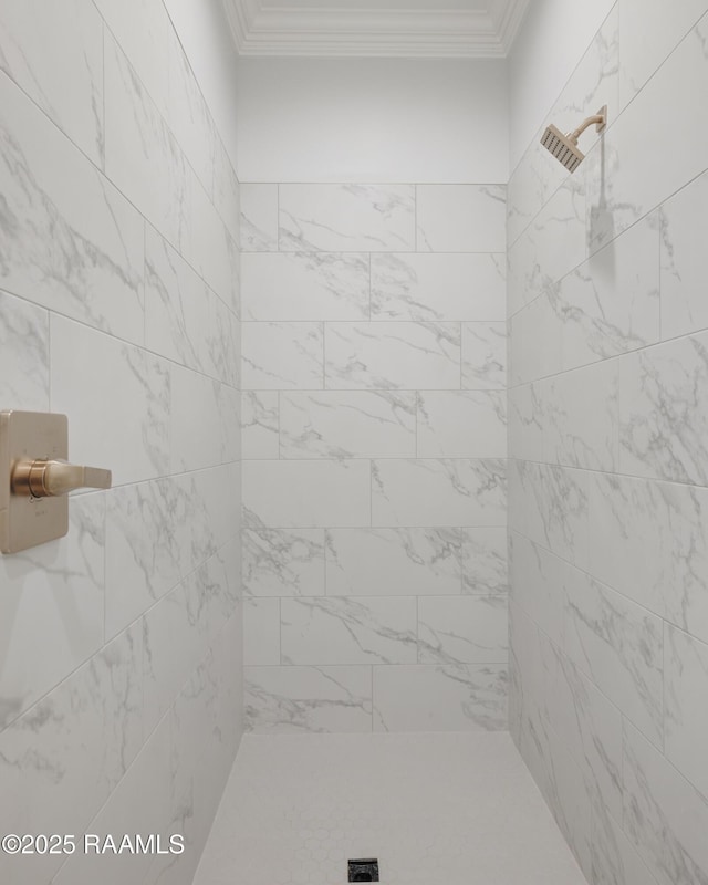 bathroom with a tile shower and crown molding