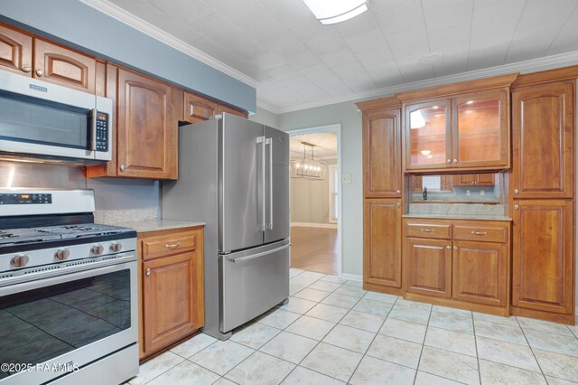 1621 Elm St, New Iberia, LA 70560 - kitchen with appliances with stainless steel finishes, brown cabinets, light tile patterned floors, a chandelier, and ornamental molding