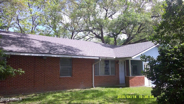 view of property exterior with brick siding, a shingled roof, and a lawn