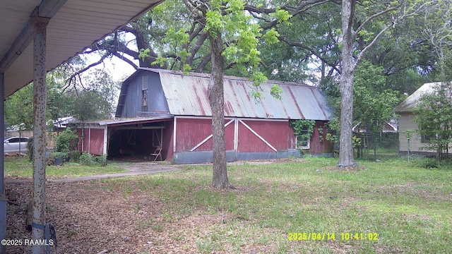 view of barn with fence and a yard