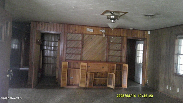 unfurnished living room featuring wood walls and carpet