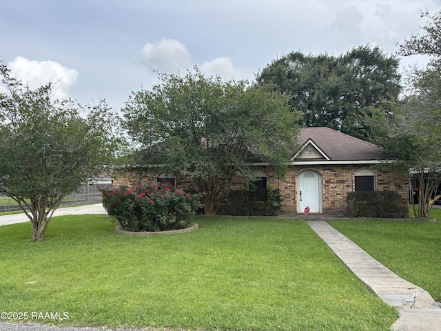 view of property hidden behind natural elements featuring brick siding, a shingled roof, and a front lawn