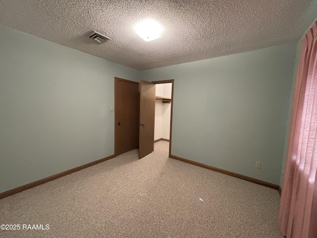 spare room with a textured ceiling, visible vents, light carpet, and baseboards