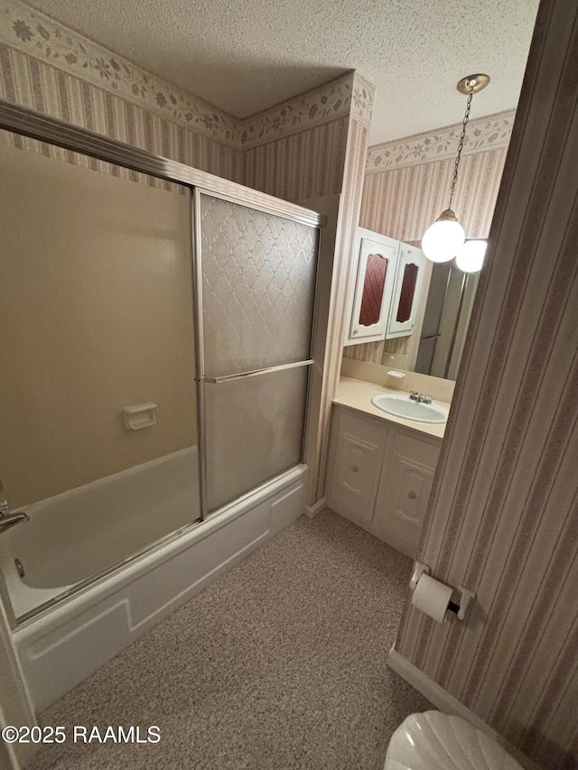 bathroom with shower / bath combination with glass door, vanity, toilet, a textured ceiling, and wallpapered walls