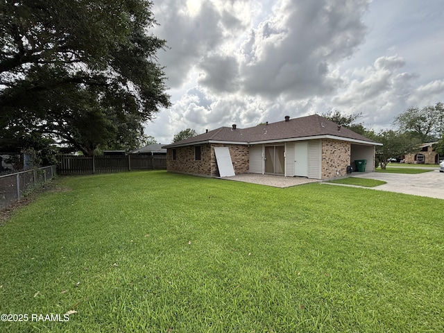 back of property featuring brick siding, a lawn, and fence
