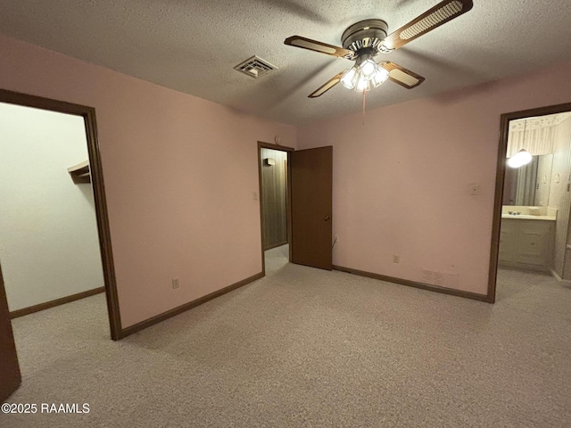 unfurnished bedroom with a textured ceiling, a spacious closet, light carpet, and baseboards