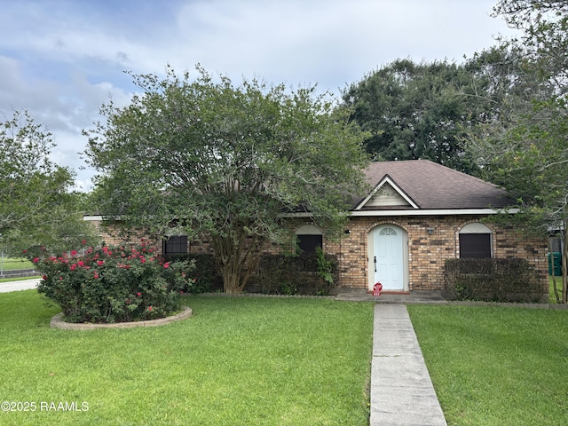 view of front of home with brick siding, a shingled roof, and a front lawn
