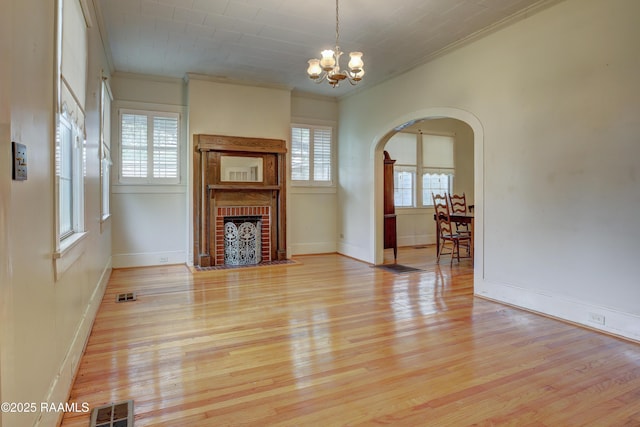 627 Weeks St, New Iberia, LA 70560 - unfurnished living room with ornamental molding, a chandelier, plenty of natural light, arched walkways, and light wood-style floors