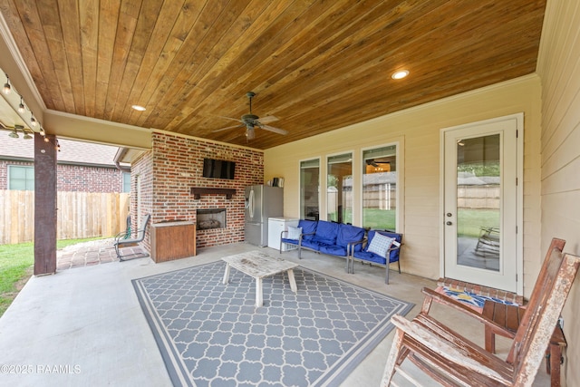 view of patio with fence, a ceiling fan, and an outdoor living space with a fireplace