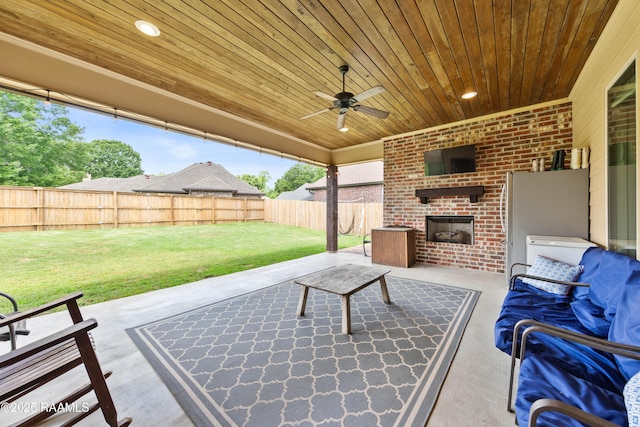 view of patio / terrace with a fenced backyard, a ceiling fan, and an outdoor brick fireplace