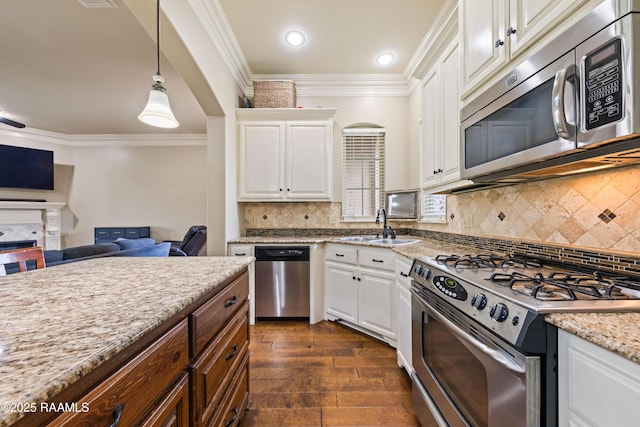 kitchen with a sink, ornamental molding, stainless steel appliances, and white cabinets