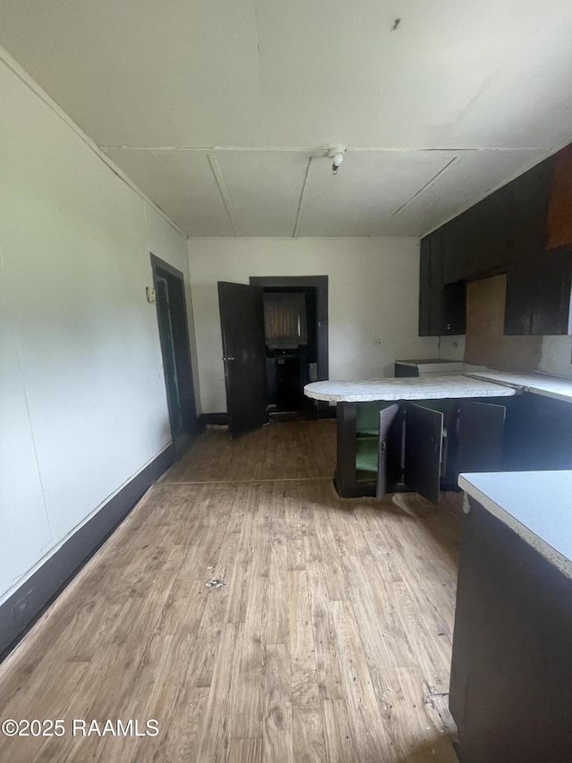 kitchen featuring light countertops, dark cabinets, and light wood finished floors