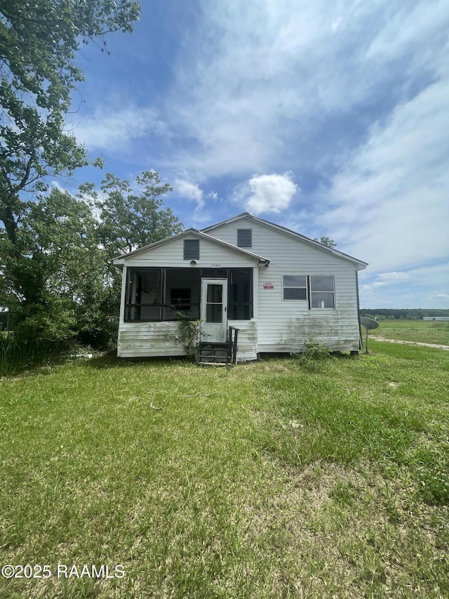 view of front facade featuring entry steps, a sunroom, and a front lawn