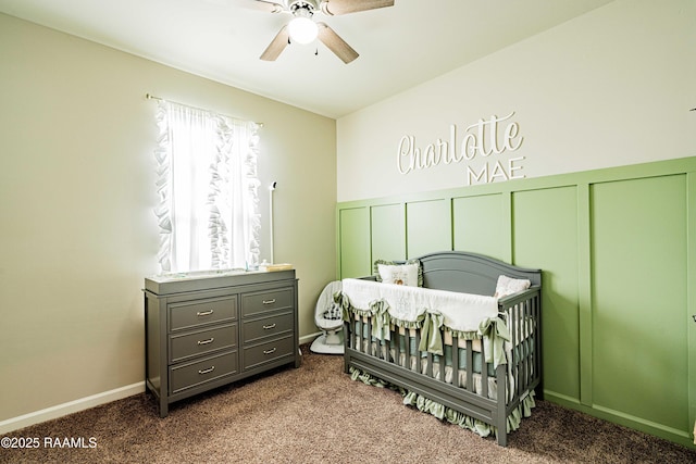 carpeted bedroom featuring a nursery area and ceiling fan