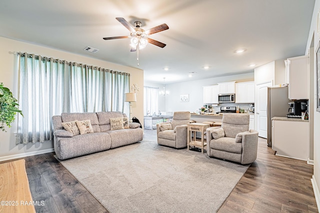 living area with recessed lighting, visible vents, dark wood-style floors, and ceiling fan with notable chandelier