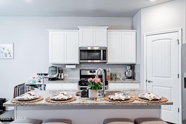 kitchen featuring a breakfast bar area, stainless steel appliances, and white cabinetry